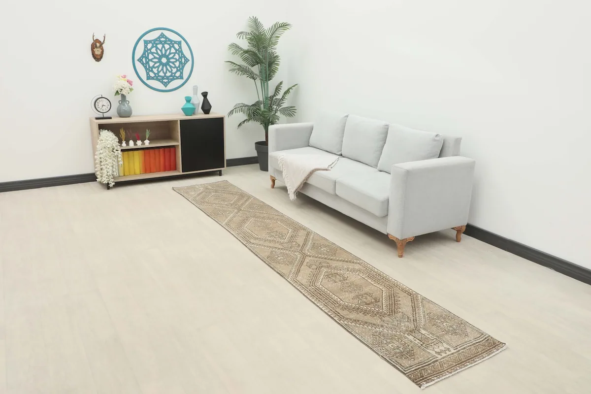 Vintage runner rug in a modern living space next to a light gray sofa, showing its full length.