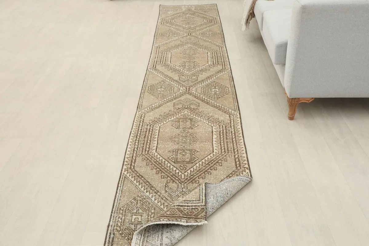 Runner rug partially unrolled in a room setting, displaying its length and pattern.