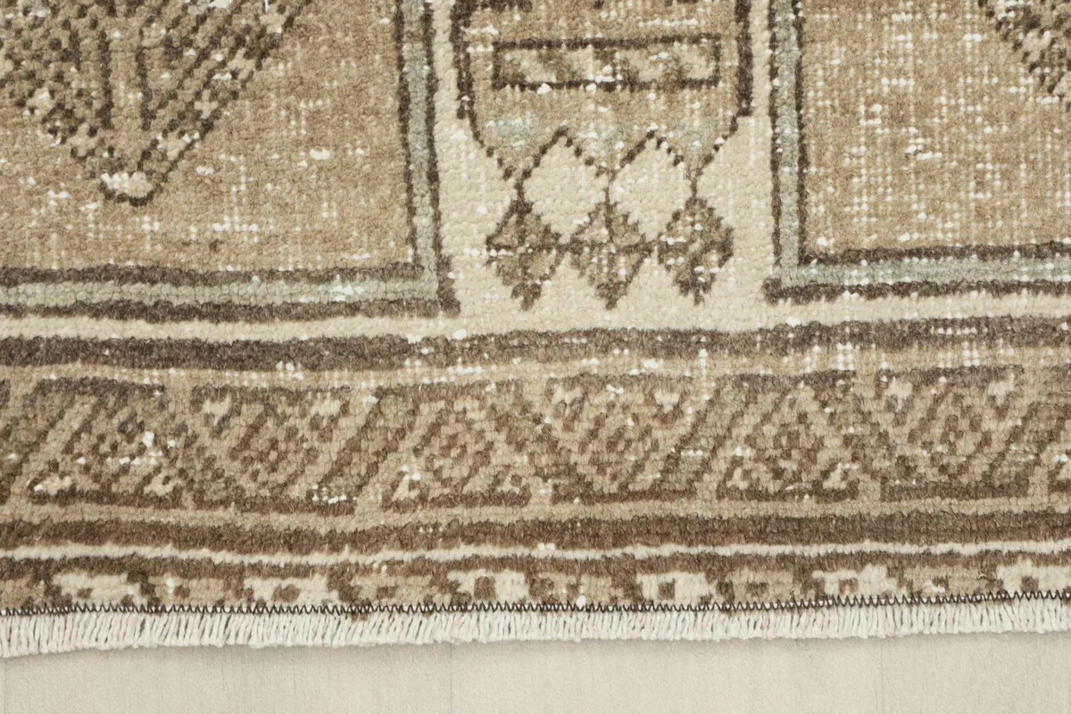 Close-up of the rug's border and fringe, showing the intricate weaving and natural fibers.