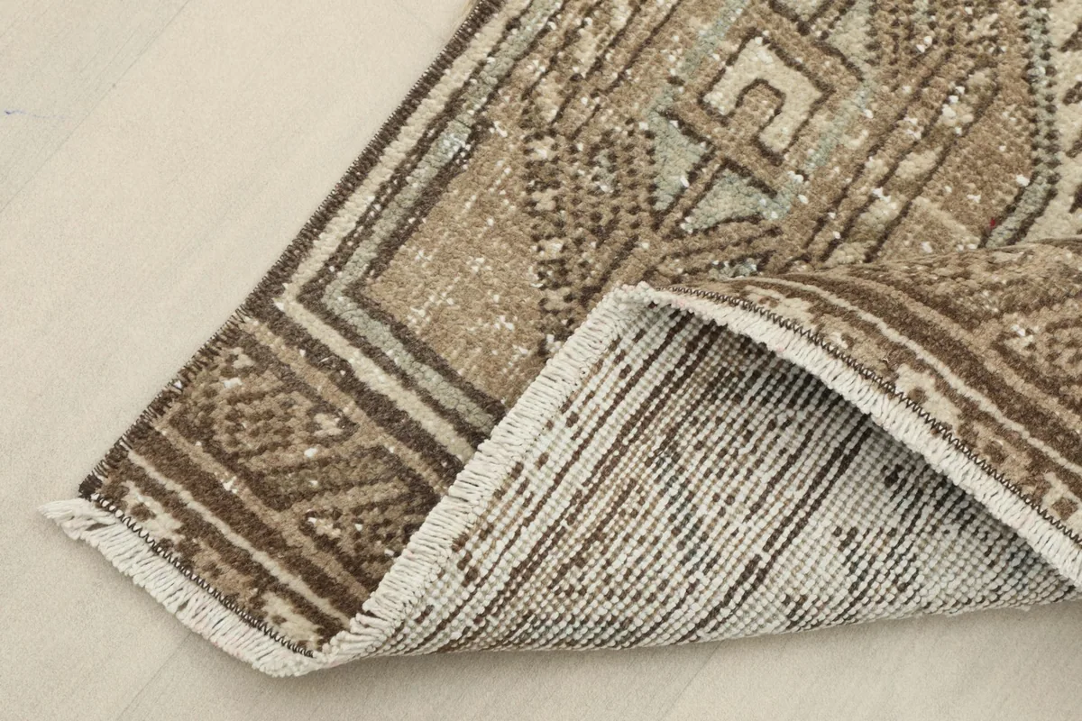 Corner of the rug folded back to show the cotton foundation and reverse side of the hand-knotted wool pile.