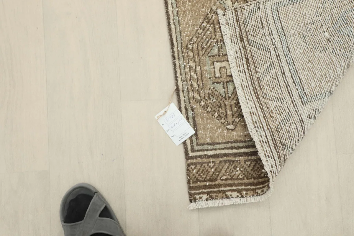 Overhead view of the rug's back, showing the foundation and a tag, with a foot for scale.