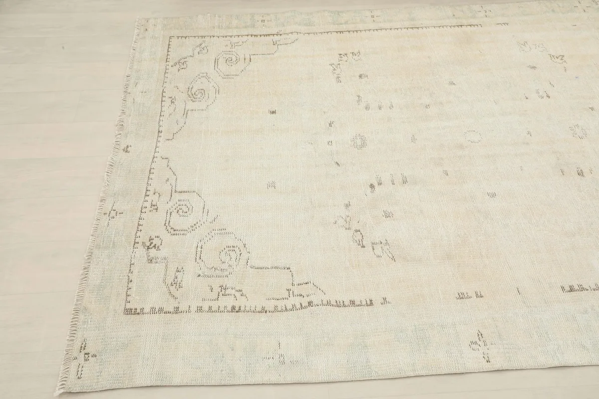 Close-up of the rug's corner with faded geometric patterns and border details