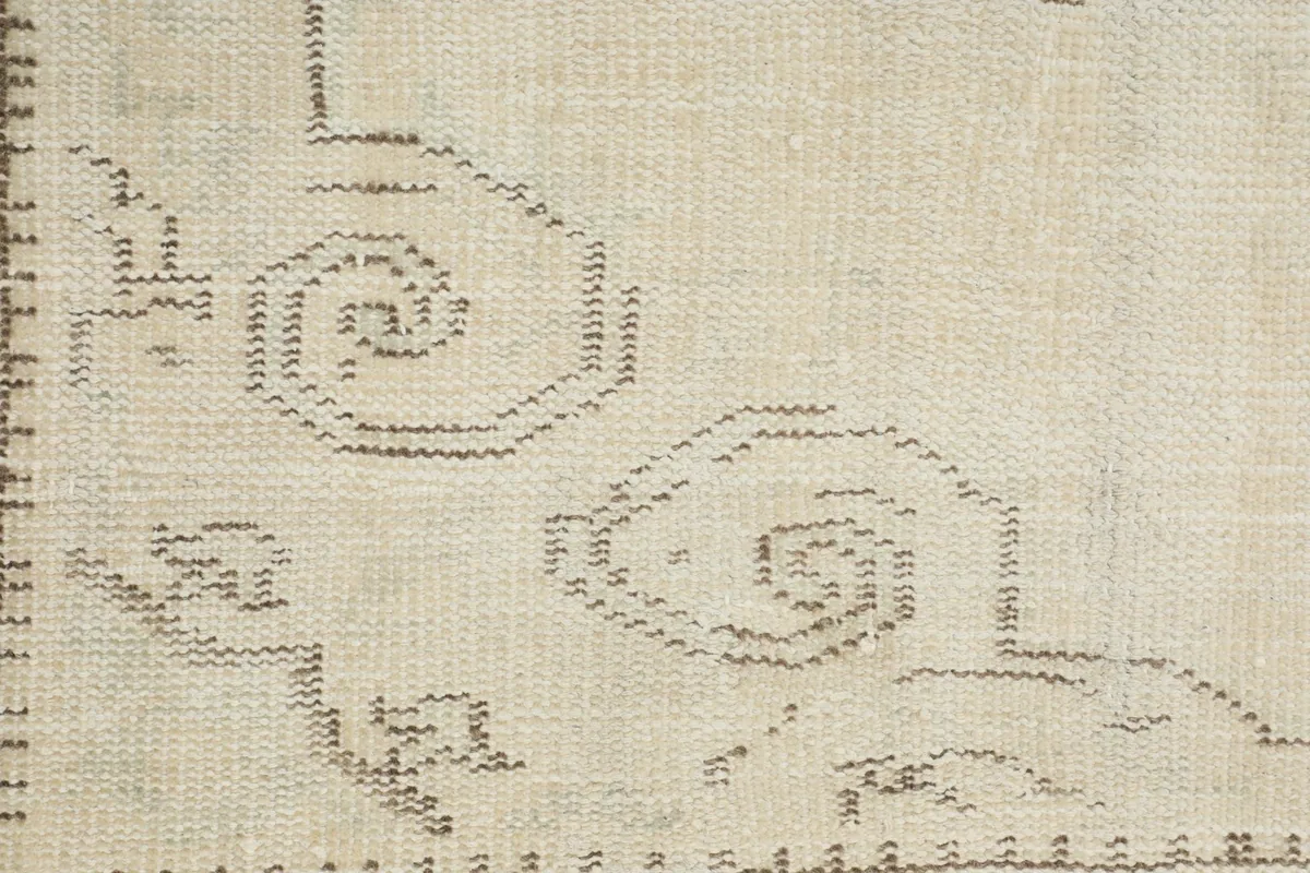 Macro view of the hand-knotted wool pile and the intricate, faded border design