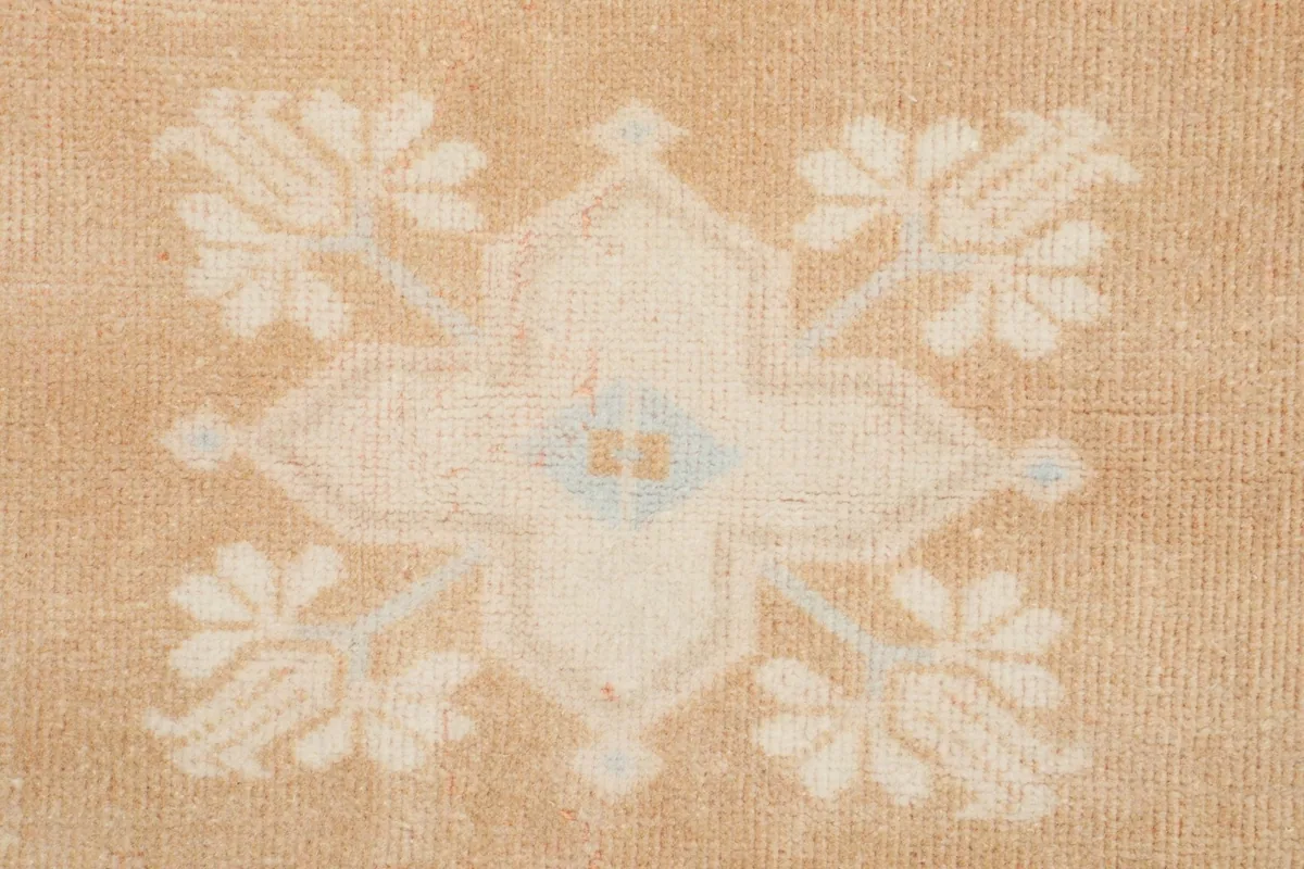 Detailed view of a central ivory floral motif with subtle blue accents in the rug's field