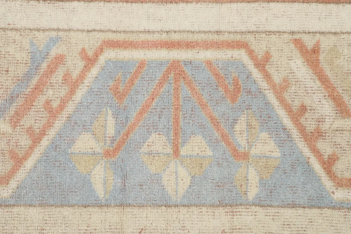 Close-up detail of the geometric motifs in blue, rust, and beige within the border design