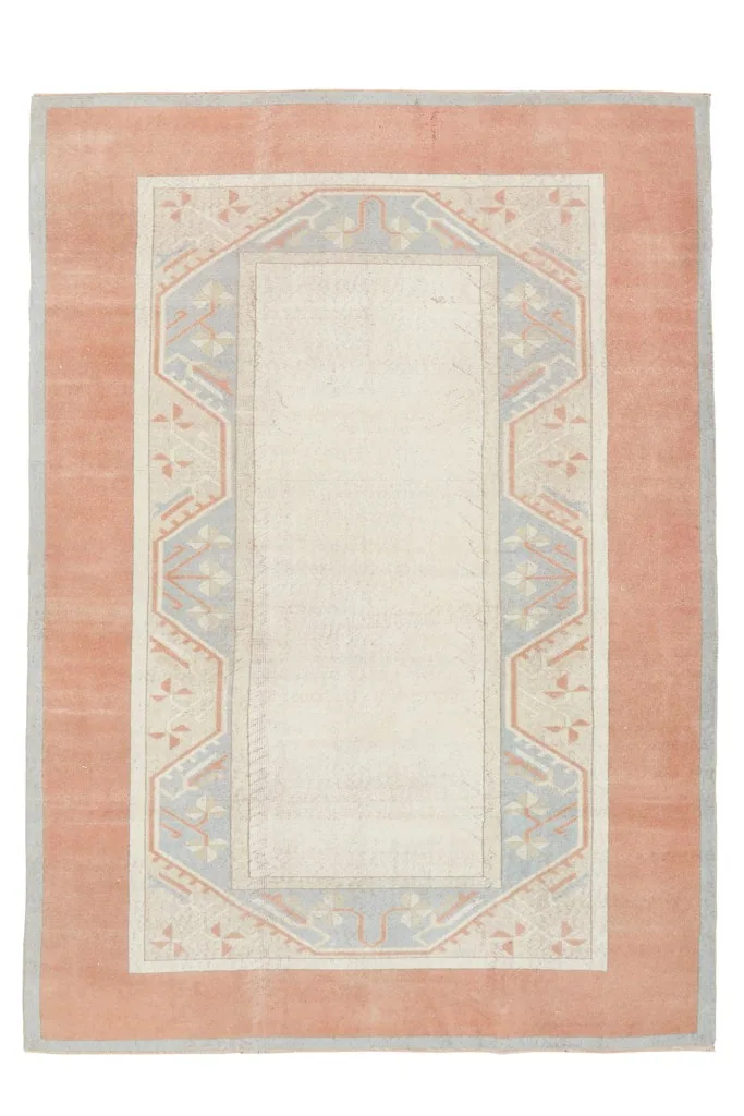 Overhead view of the hand-knotted wool rug, showing its rust field and ivory center