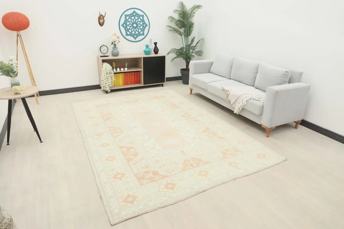 Large ivory and orange rug displayed in a living room setting with a light gray couch