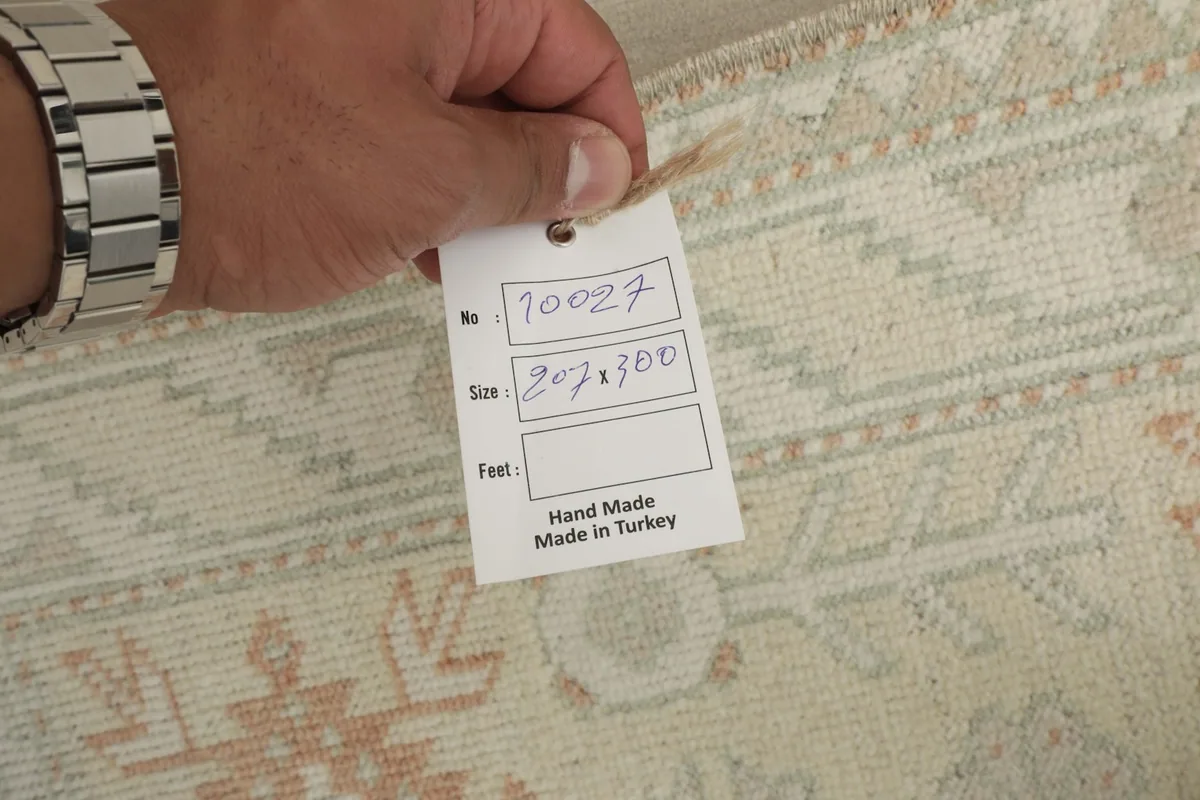 Hand holding a tag indicating the rug's origin as handmade in Turkey