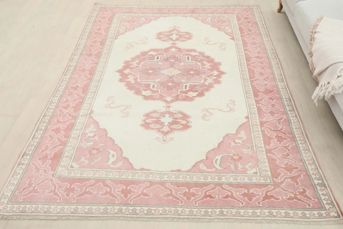 Overhead view of the rose and ivory vintage rug in a living room, showcasing its full design.