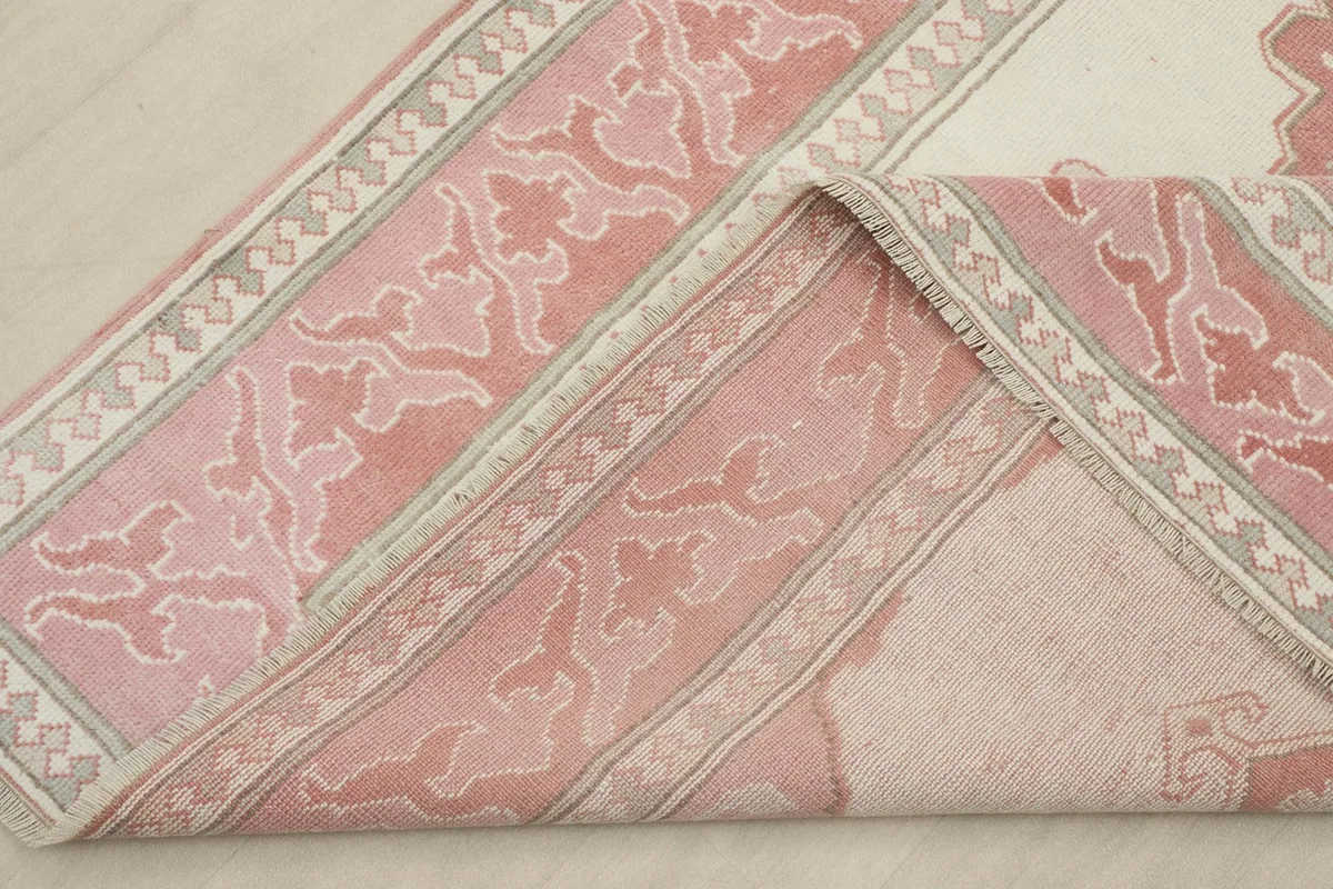 A section of the rug folded back, revealing the reverse side of the hand-knotted wool on cotton foundation.