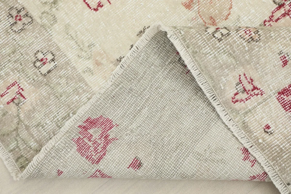 Folded corner of the rug, exposing the cotton foundation and the reverse side of the knots