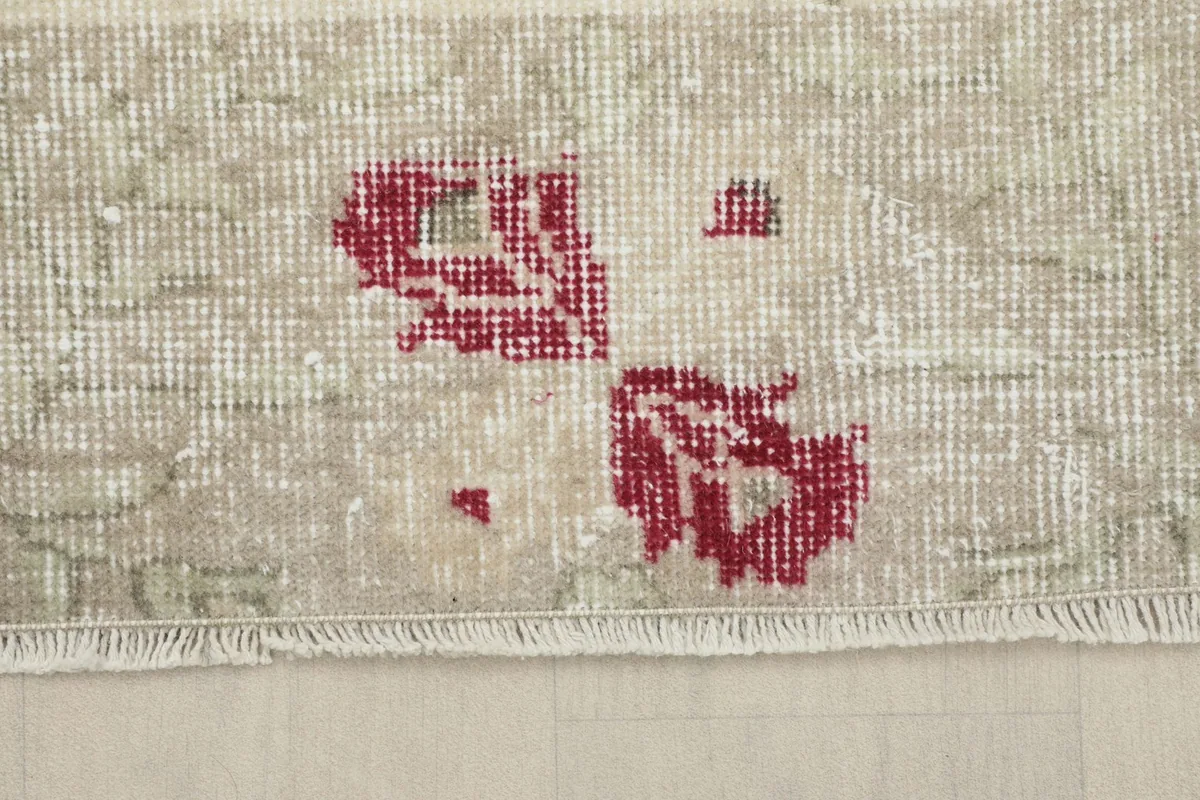 View of the rug's edge, showing the short, natural fringe and the faded colors
