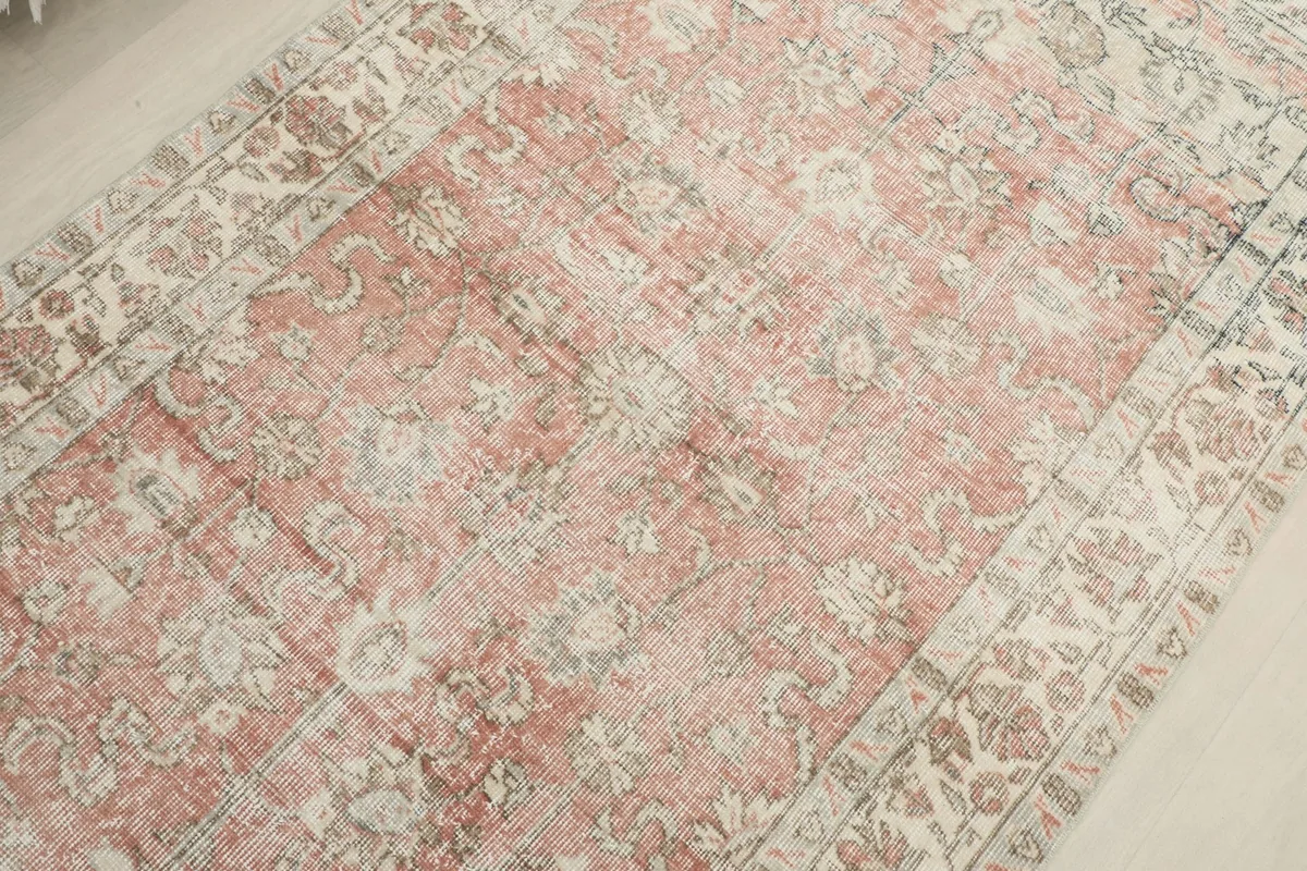 Mid-section detail of the rug's rose field, revealing the distressed wool pile and underlying patterns