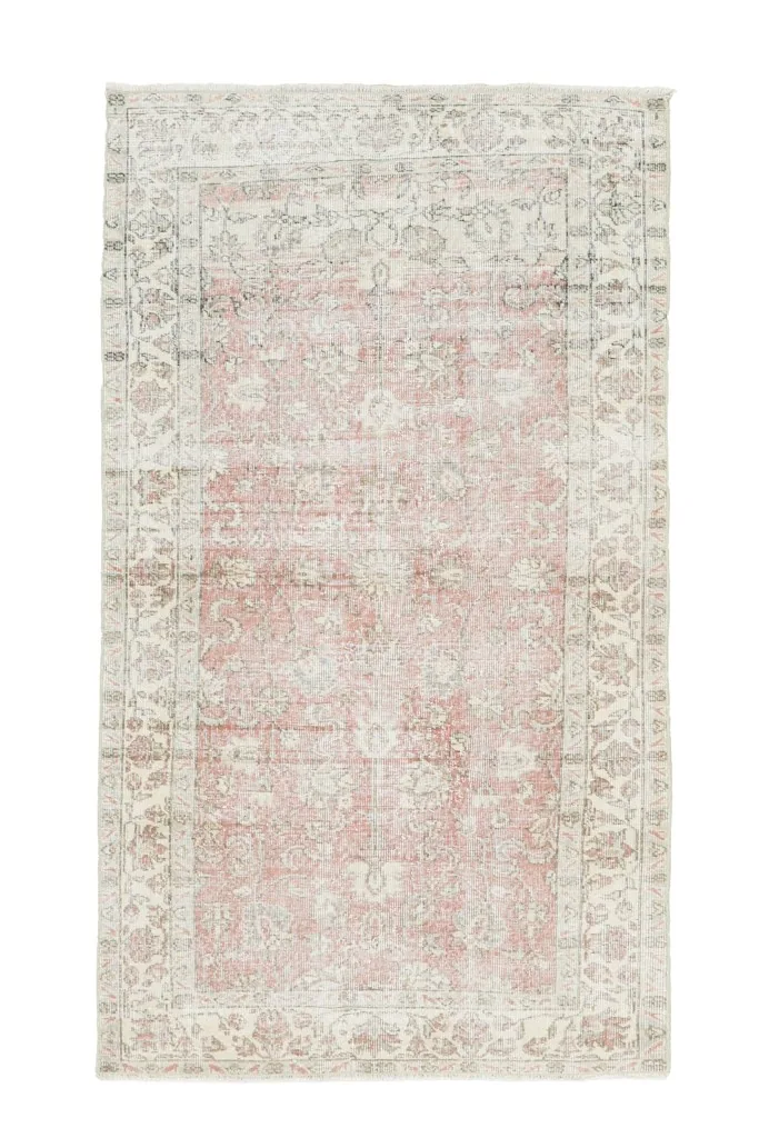 Overhead view of the hand-knotted Anatolian rug showing its faded rose field and ivory border