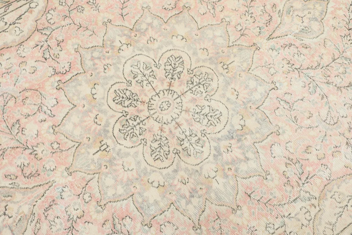 Detailed view of the central medallion motif with its subtle rose and gray tones.