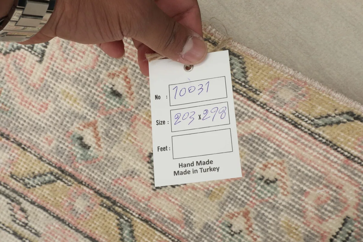 Hand holding a tag showing the rug's product number and dimensions in centimeters.