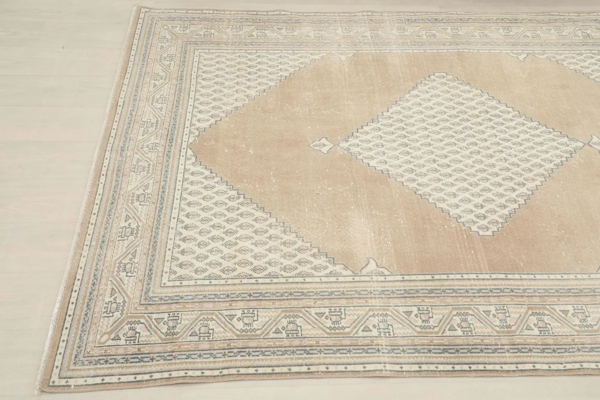 Angled view showcasing the subtle color variations and texture of the vintage tan area rug