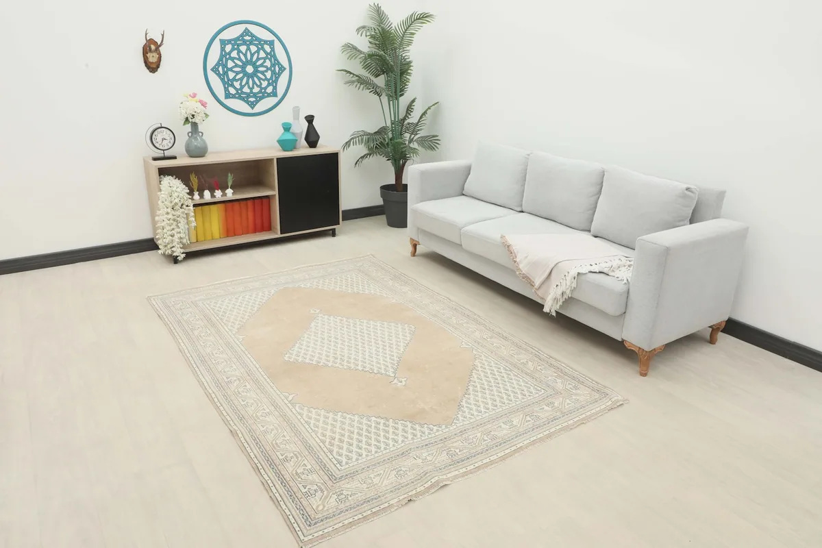 Vintage tan and beige geometric rug placed in a living room setting with a light gray sofa