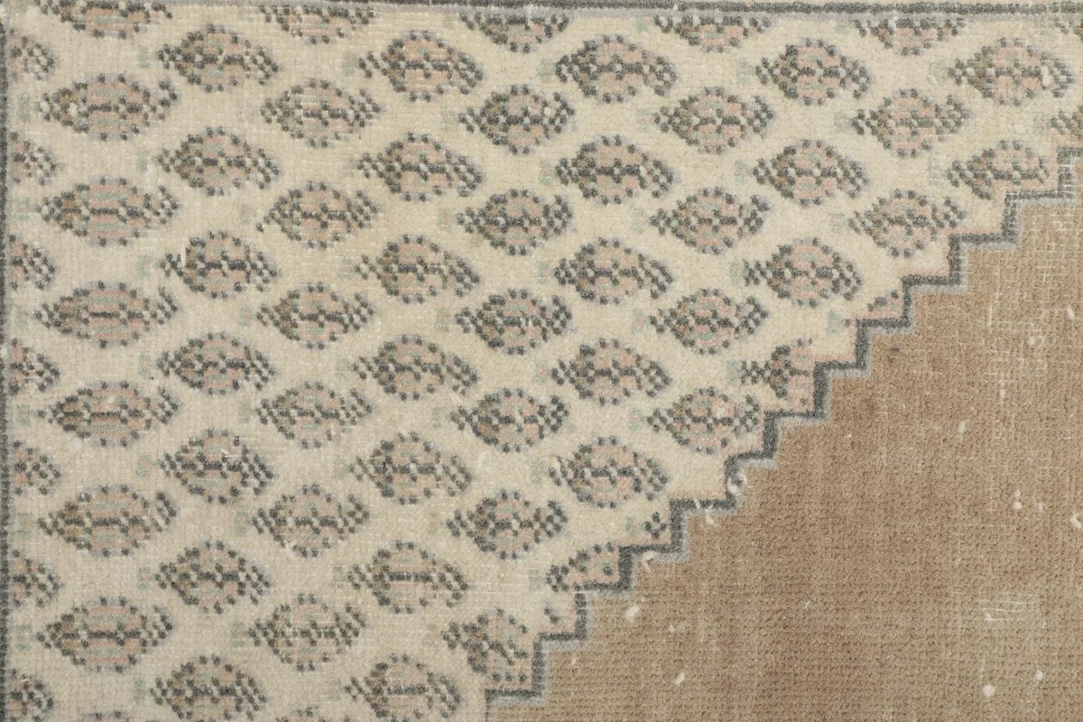 Close-up of the detailed geometric patterns within the beige and gray sections of the rug
