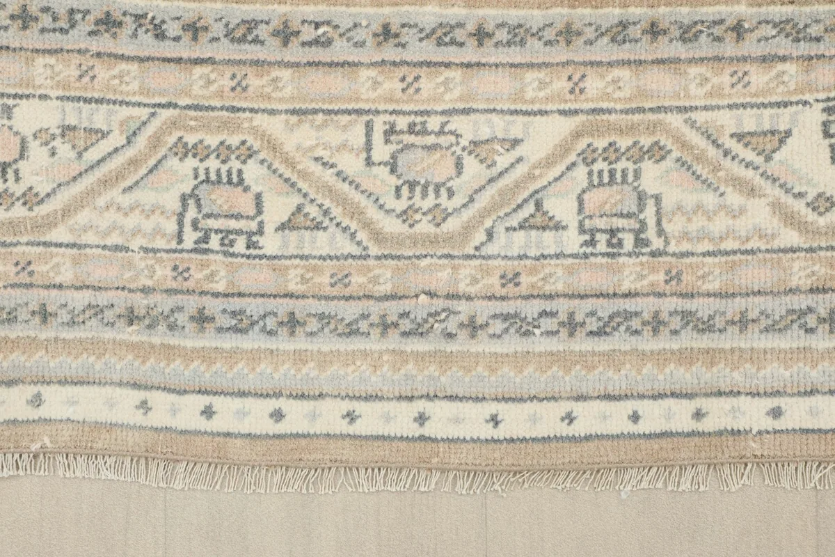 Detailed view of the intricate border design with geometric motifs in beige, gray, and blue