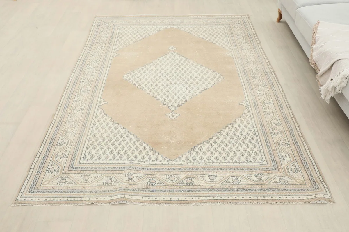 Full overhead view of the tan and beige geometric area rug in a room setting next to a sofa