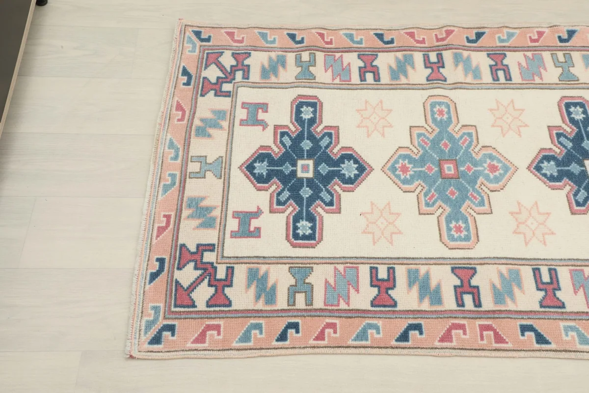 Close-up angled view of the top left section of the rug, detailing the geometric patterns and colors