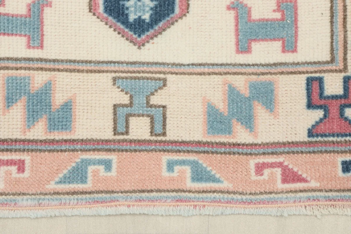 Close-up of the border design, featuring small blue, rose, and tan tribal elements