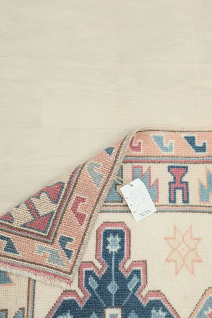 Underside of the rug with a tag, showing the hand-knotted foundation and tight weave