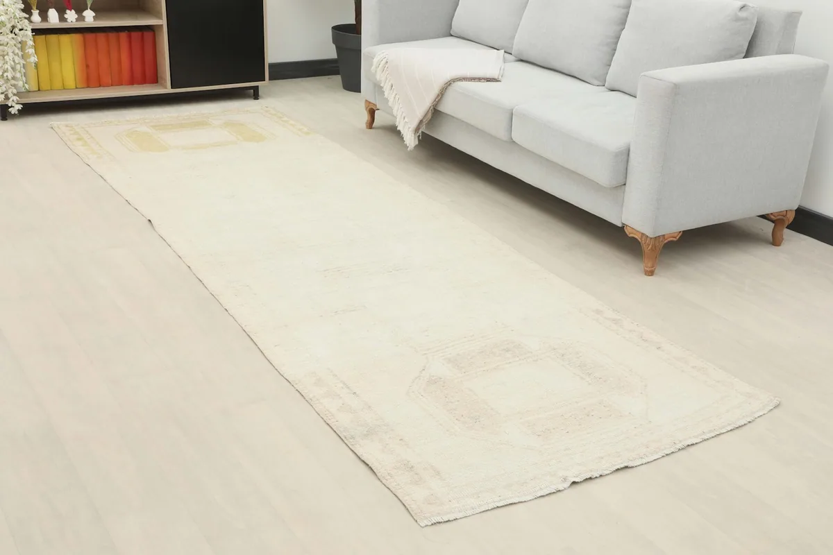 Angled view of the vintage ivory runner rug extending from a console towards a sofa in a home setting.