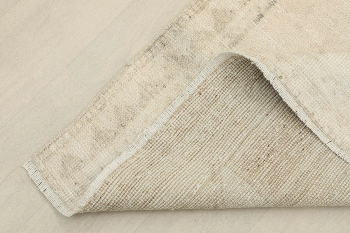Corner of the runner folded back, revealing the hand-knotted cotton foundation and reverse side.