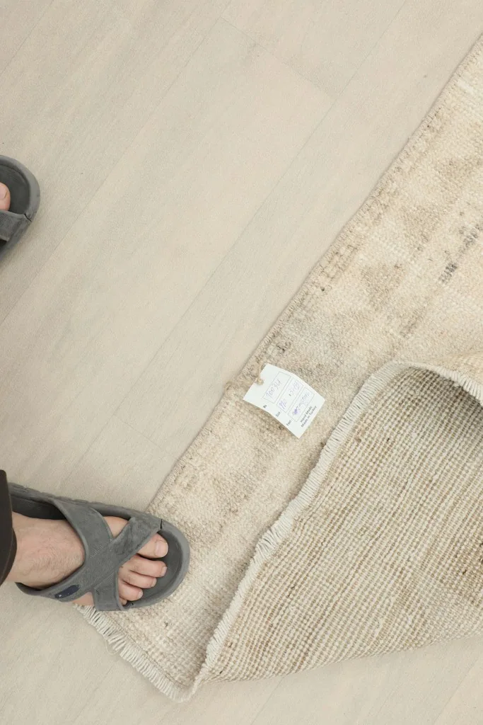 Foot in a sandal next to a corner of the rug, showing the scale and the back of the rug.