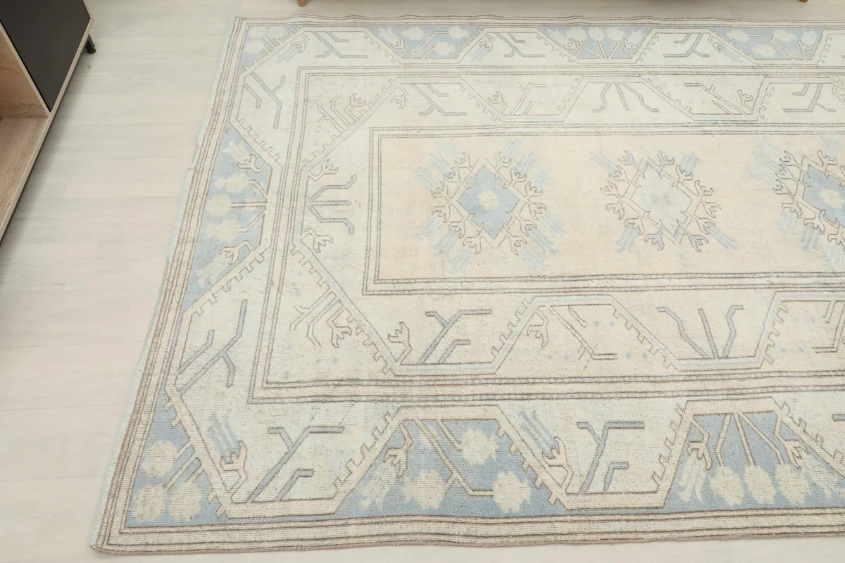 Angled view highlighting the blue border and ivory field of the hand-knotted rug