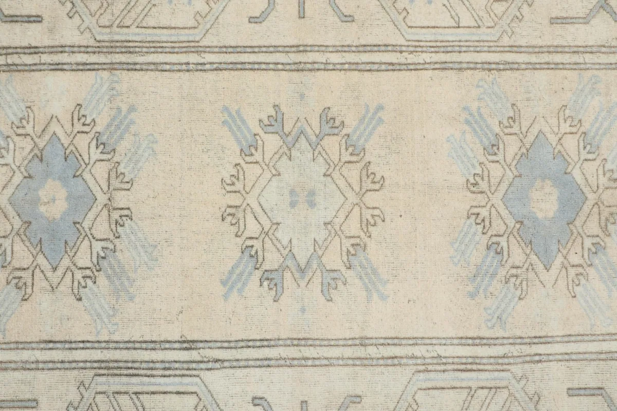 Close-up of multiple geometric motifs and the low pile texture of the vintage rug