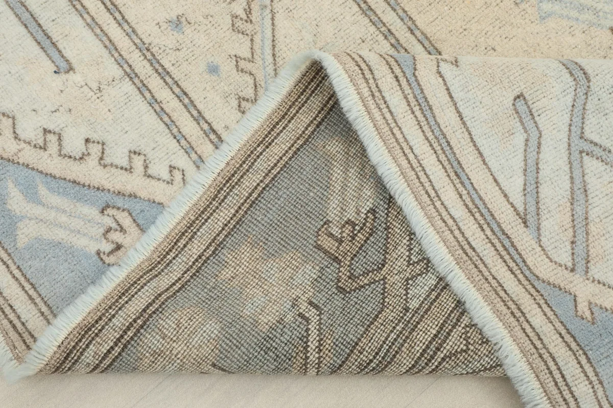 Folded corner of the rug revealing the cotton foundation and reverse side of the knots
