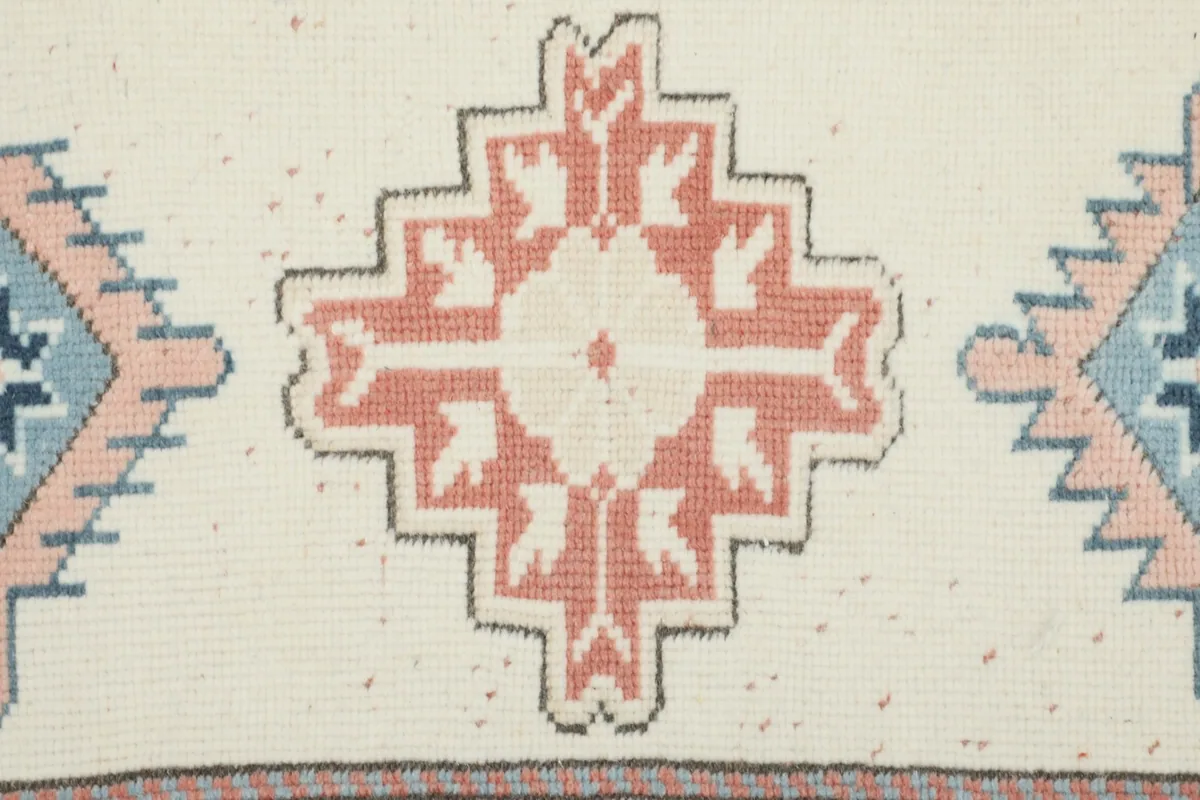 Detailed view of a single rose and ivory geometric medallion motif in the runner's center.