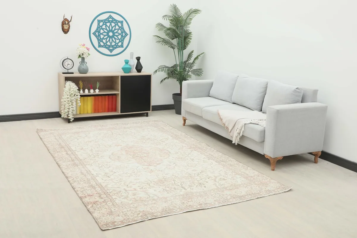 Ivory and rose vintage Anatolian rug placed in a modern living room setting with a light gray sofa.