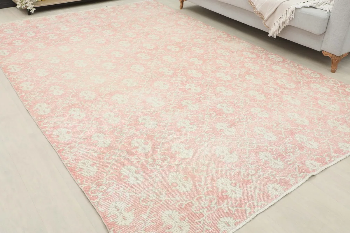 Angled view of the vintage pink rug, highlighting its floral and geometric patterns