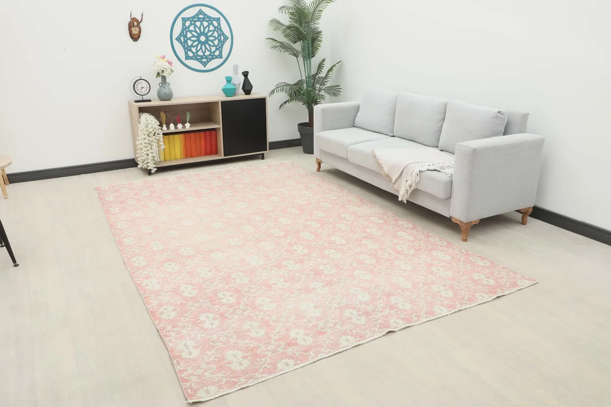 Large pink and ivory vintage area rug displayed in a living room setting with a sofa
