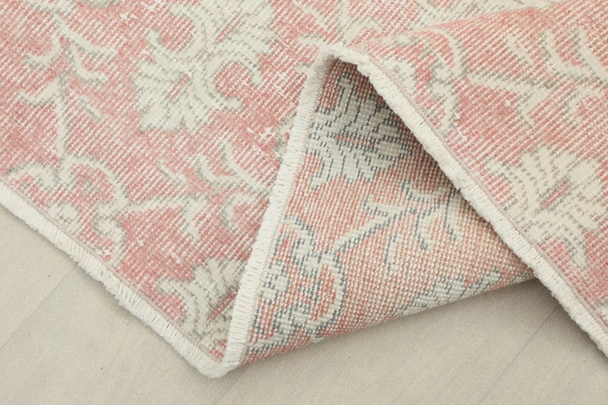 Corner of the rug folded to show the hand-knotted back and wool pile texture