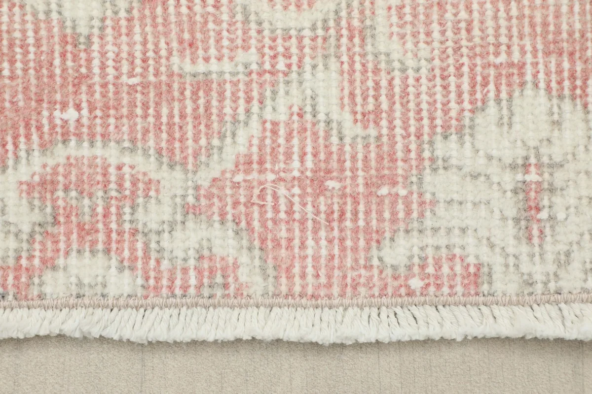 Detail of the short, delicate ivory fringe along the edge of the vintage pink rug