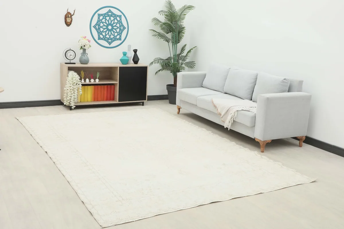 Ivory vintage Anatolian rug displayed in a living room setting with a light gray sofa