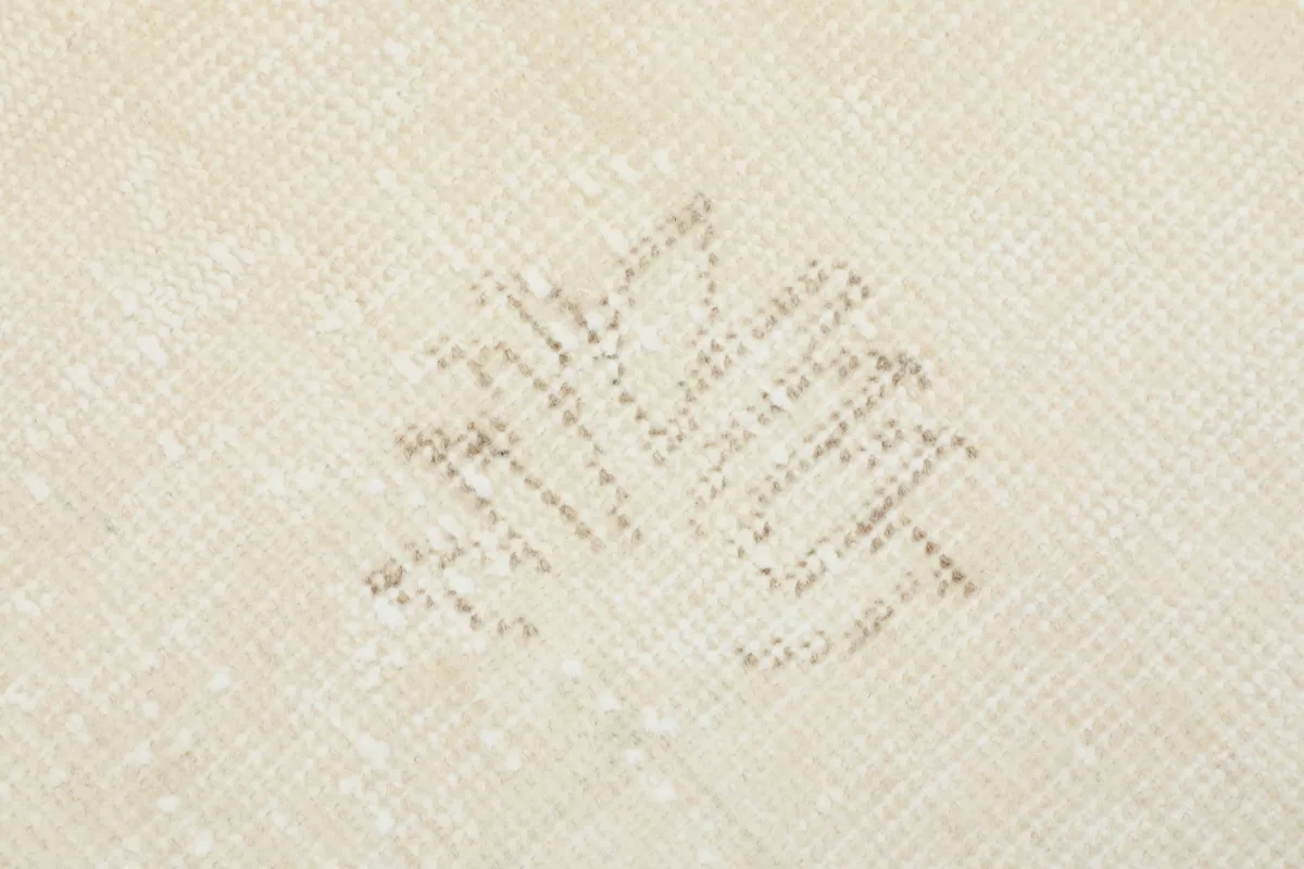 Macro detail of a faded geometric motif within the ivory rug's field