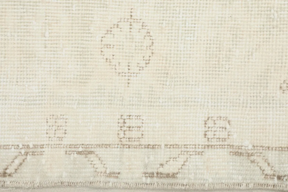 Detail of the outer border and a small geometric motif on the ivory vintage rug