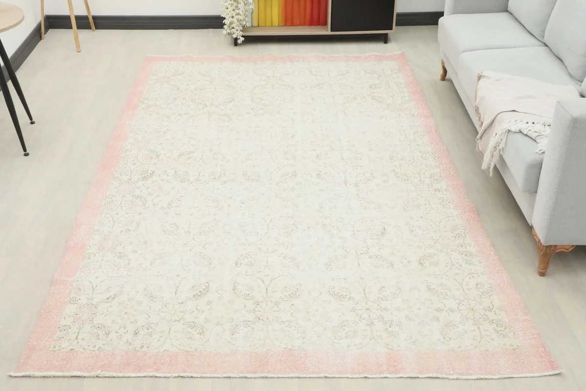 Full room view of the large ivory and rose vintage rug, showcasing its scale and overall aesthetic
