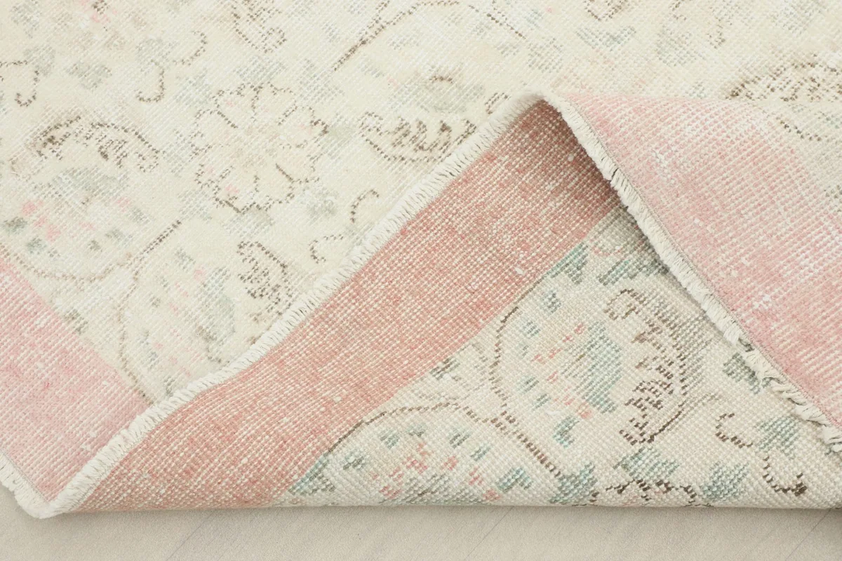 Corner of the rug folded back, revealing the wool pile on cotton foundation and the reverse side