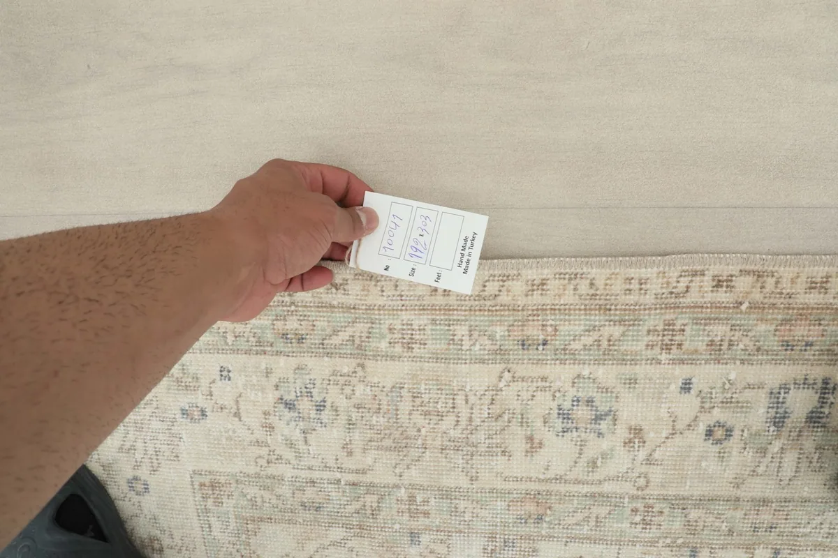 Hand holding a measurement card next to the rug to indicate scale and pile height