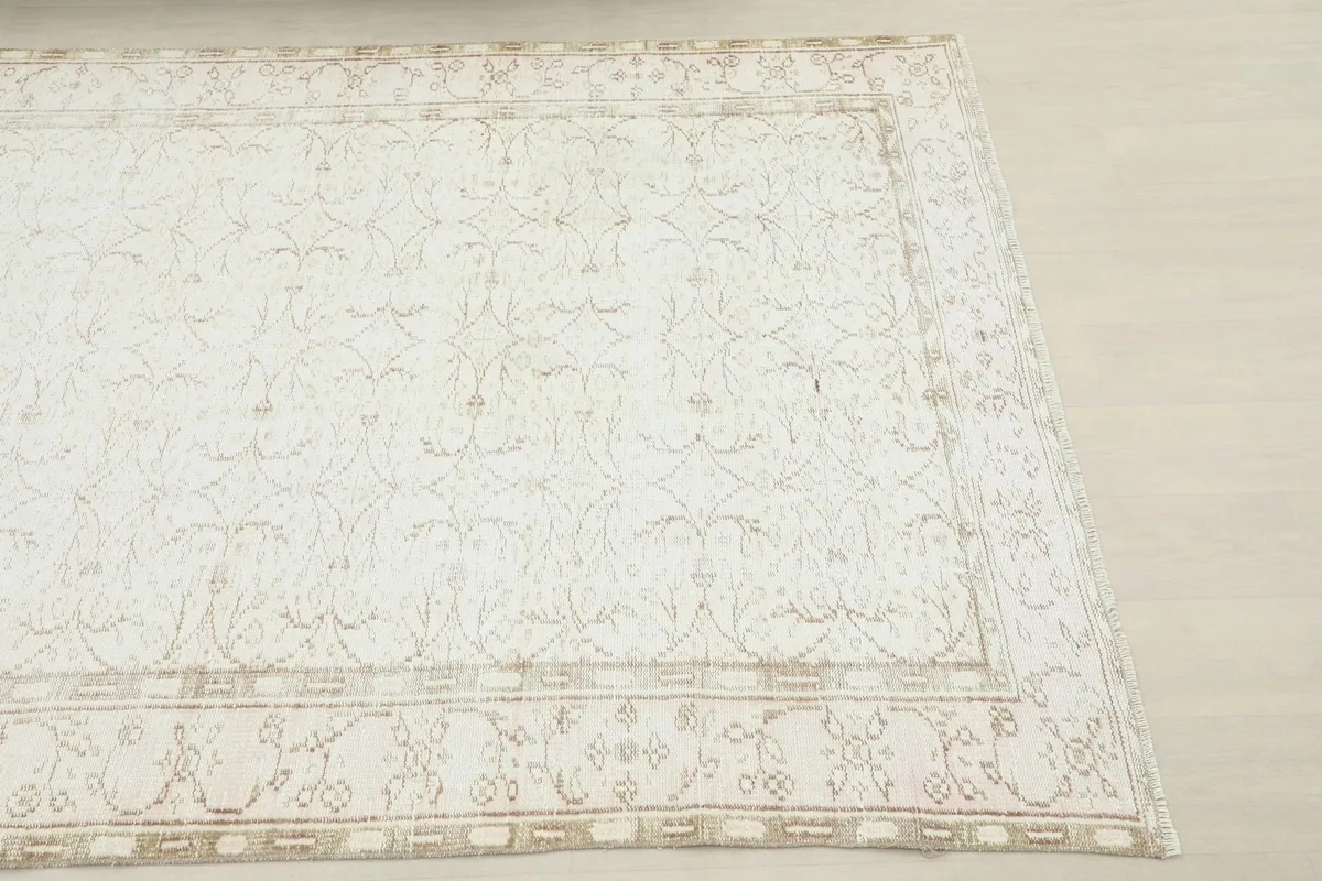 Close-up of the rug's corner, highlighting the distressed beige border and ivory field pattern.