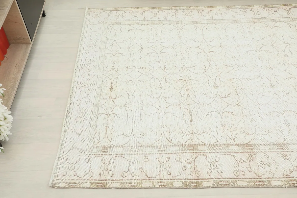 Detail shot of the rug's surface, showing the faded floral design and natural wear.