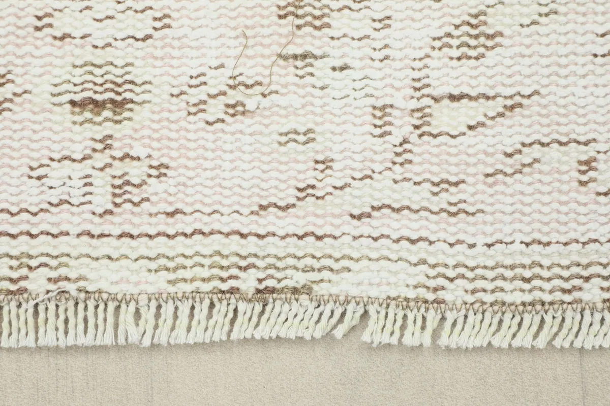 Detail of the rug's fringe and the edge, showing the natural finish and subtle wear.