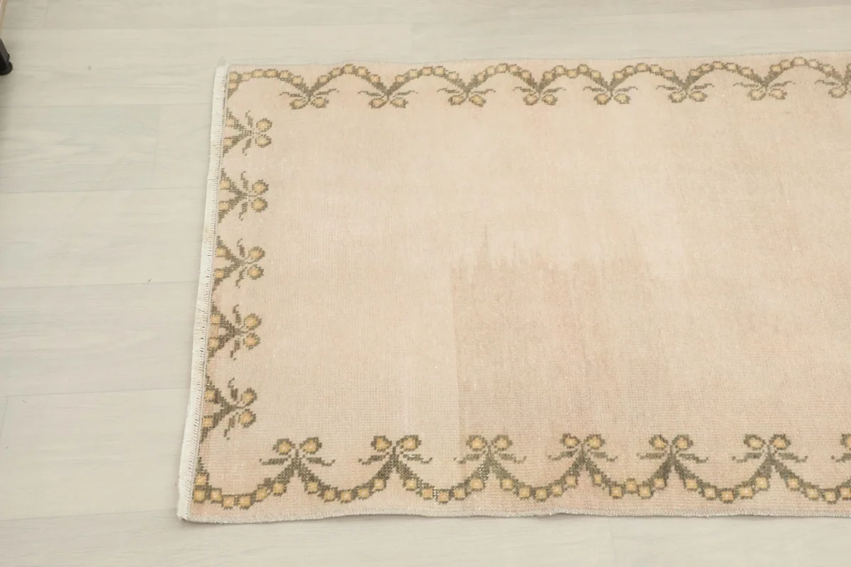 Close-up detail of the other end of the beige runner rug, showing the consistent border design.